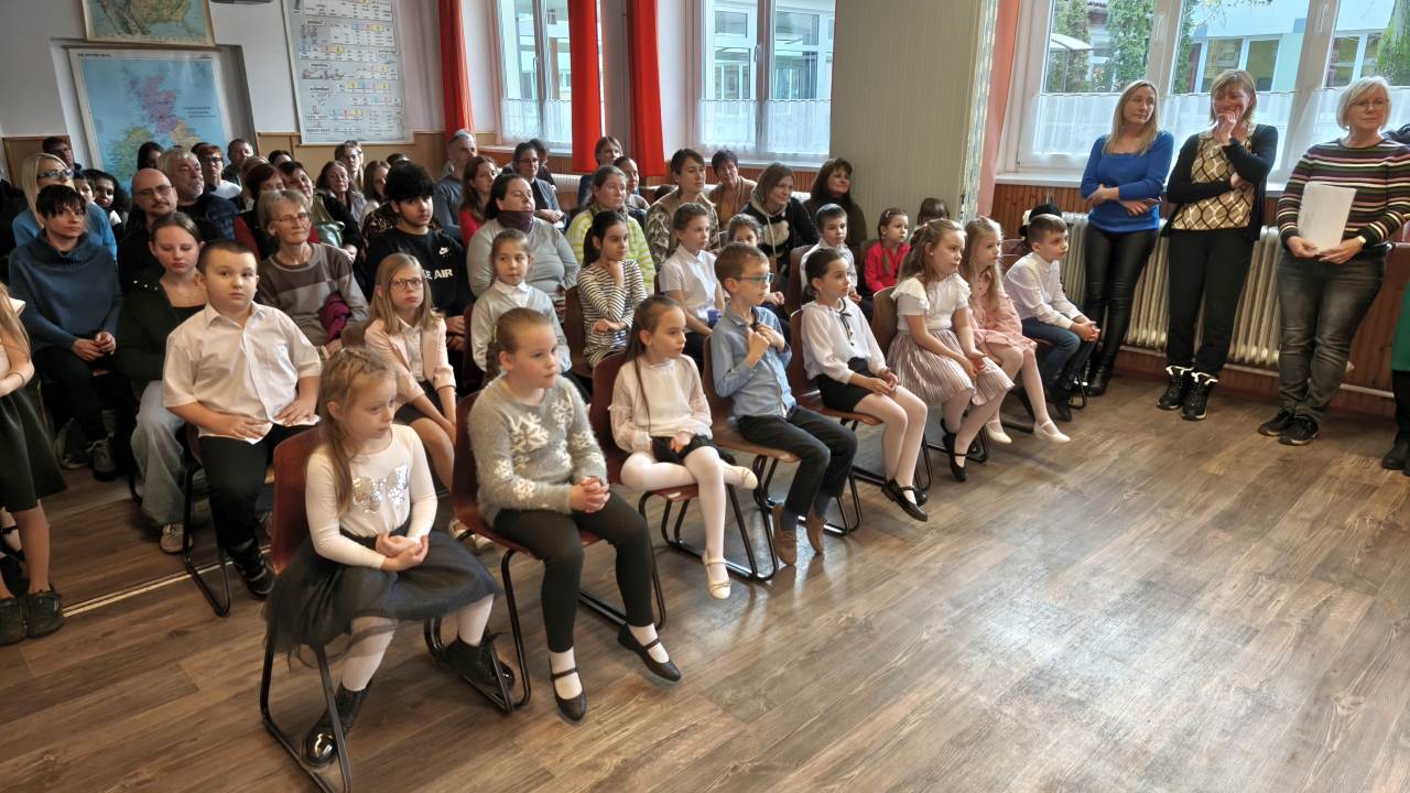 Mesemondó versenyen figyelmesen hallgató diákok és pedagógusok. Iskolai rendezvény gyerekek és felnőttek részvételével.